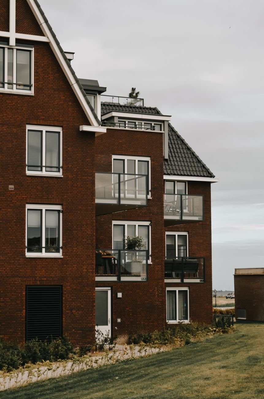 A contemporary residential building with glass balconies and brick facade.